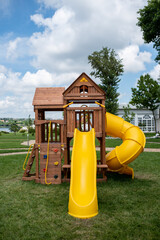 Wooden playground with yellow slides on a green meadow 