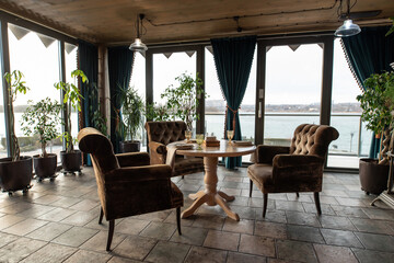 Beautiful interior of the restaurant in semi-antique dark brown shades. Served tables. Panoramic windows 