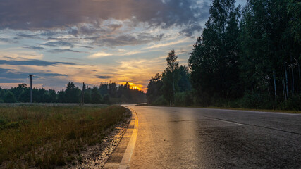 Obraz premium Sunset in the fields on wet asphalt.