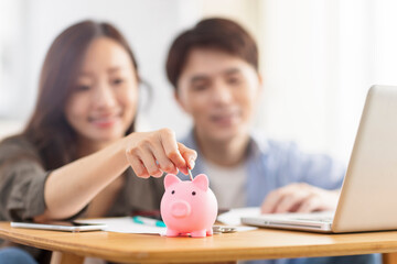 Obraz na płótnie Canvas Happy couple inserting coin in piggybank.Family finance.Focus on piggybank.
