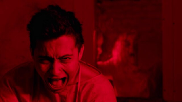 Mad man sitting in the mental hospital in straitjacket and screaming with a scary girl on the background