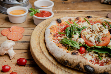 Artisan pizza with tomato, chesse and arugula on a wooden table