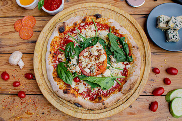 Artisan pizza with tomato, chesse and arugula on a wooden table