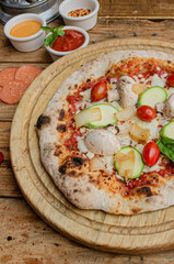 Artisan vegetarian pizza with tomato, chesse and basil on a wooden table