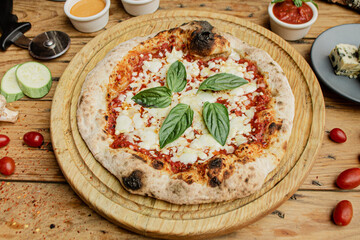 Artisan pizza with tomato, chesse and basil on a wooden table