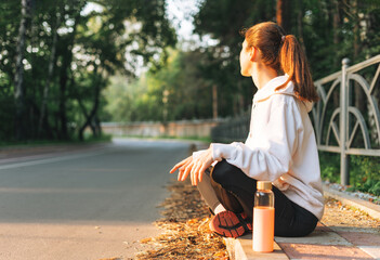 Young slim woman brunette in sport clothes running at autumn park on golden hour sunrise time....
