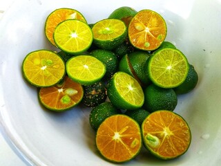 sliced ​​green oranges placed on a white plate