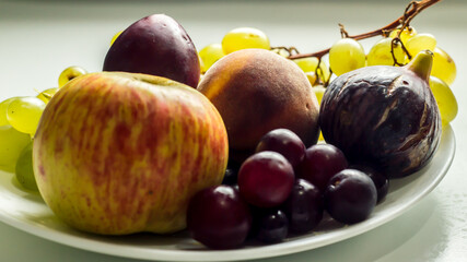 A close up to a good assorted fresh fruits in a white plate 