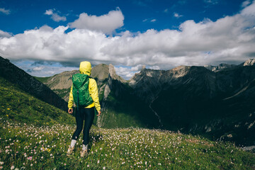 Successful woman backpacker hiking on alpine mountain peak