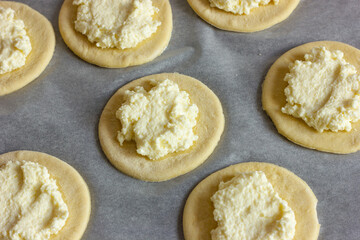 a circle of dough with cottage cheese filling on the table, cooking cheesecakes with cottage cheese