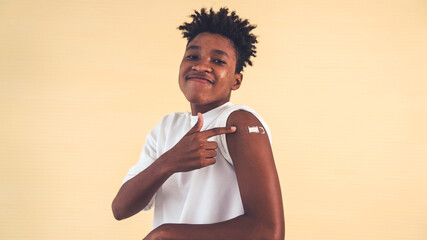 African American teenager showing COVID-19 vaccine bandage merrily in concept of coronavirus...