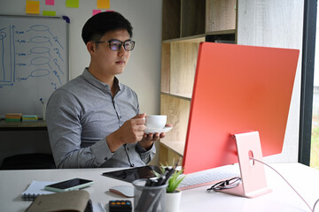 Thoughtful businessman drinking coffee and analyzing financial data on computer.