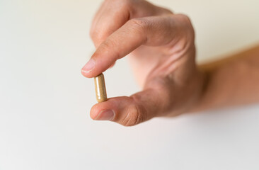 Close up hand with herb capsule on white background. Microdosing concept. Psychedelics therapy....