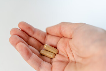 Close up hand with herb capsule on white background. Microdosing concept. Psychedelics therapy. Depression, anxiety treatment 