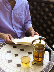 自宅ベランダでお茶を片手に読書を楽しむ男性