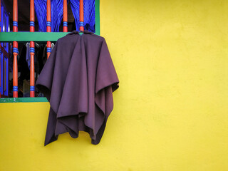 A poncho hanging from a wooden window in guatape, colombia