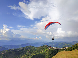 Two men paragliding in the mountains of mainzales in colombia, during a great sunny day with some clouds in the landscape