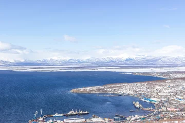 Fotobehang A settlement in the north, houses covered with snow and a seaport. Winter landscape with mountains. the concept of life beyond the arctic circle. © Павел Чепелев