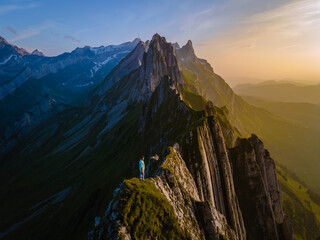 Schaefler mountain ridge swiss Alpstein, Appenzell Switzerland, steep ridge of the majestic Schaefler peak, Switzerland. couple man and woman mid age in the mountains, man hiking looking forward