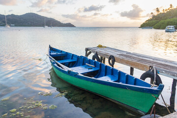 Naklejka na ściany i meble A green wooden boat docked in a handcrafted deck of Providencia Island in Colombia