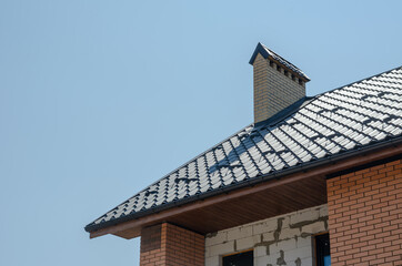 Unfinished Redbrick cottage with brown roof and chimney against