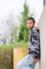 Teenager sitting on fence wearing sweatshirt and jeans