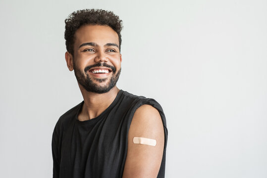 Man smiling after receiving vaccination, young men received a corona vaccine looking away isolated on gray background.