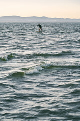 Man on sup board paddling far away