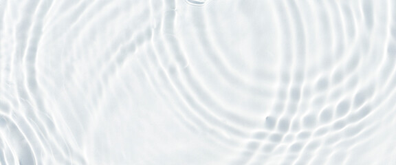 Water droplets fall on the transparent surface of the water in sunlight. Top view, flat lay. Banner
