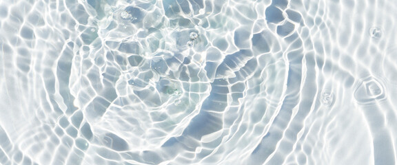 Obraz premium Water droplets fall on the transparent surface of the water in sunlight. Top view, flat lay. Banner