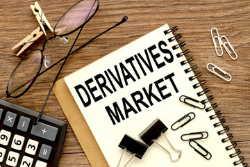 DERIVATIVES MARKET. notepad and glasses on wood background