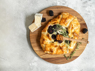 Baked brie cheese and blackberry open pie galette with thyme and honey. Homemade puff pastry baking, sweet-savory taste, gourmet appetizer. - obrazy, fototapety, plakaty