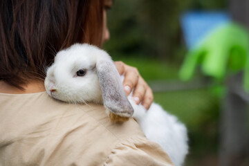 Asian woman holding and carrying cute rabbit with tenderness and love. Friendship with cute easter...