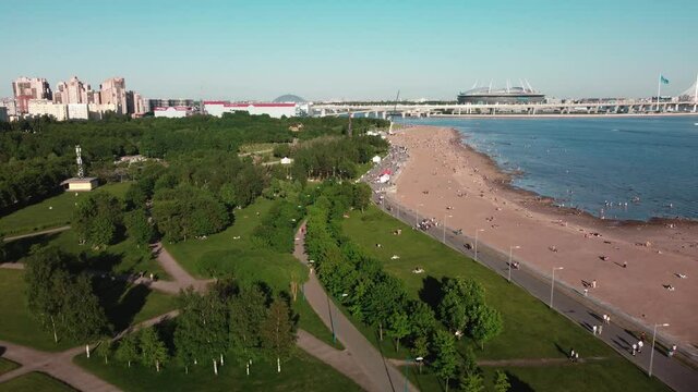 Drone flight over the city beach on a sunny day, where many people are resting. Flight over the park of the 300th anniversary. Saint Petersburg, Russia