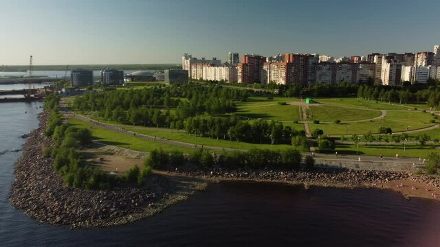 Drone flight over the city beach on a sunny day, where many people are resting. Flight over the park of the 300th anniversary. Saint Petersburg, Russia