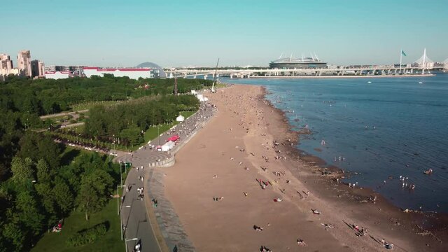 Drone flight over the city beach on a sunny day, where many people are resting. Flight over the park of the 300th anniversary. Saint Petersburg, Russia