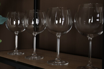 Empty wine glasses on shelf near brown wall