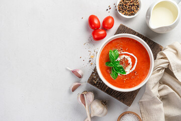 Tomato soup-puree with cream on a gray background with ingredients. Top view, copy space.