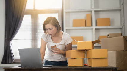 Asian woman business owners checking online orders to prepare to pack the parcels, sell to customers.E-commerce , Online Shopping ideas.