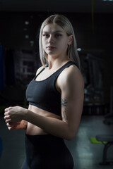 Young beautiful blonde girl is engaged in the gym. Photographed in a low key.
