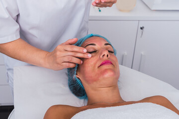 Fototapeta na wymiar Cosmetologist applying facial massage cream to face of a woman in the beauty spa