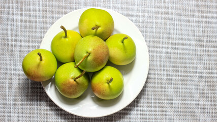 Ripe green pears in a plate on the table.