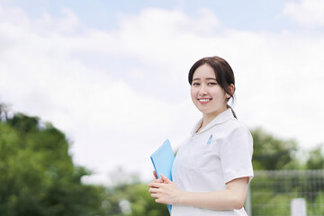 青空背景で笑顔で立つ女性看護師