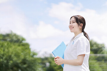 青空背景で笑顔で立つ女性看護師