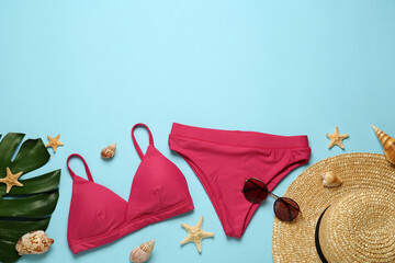 Stylish bikini and beach accessories on light blue background, flat lay. Space for text