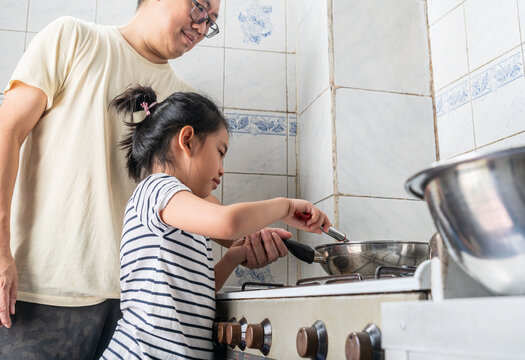 Asian Child Girl Cooking With Father In A First Time, Using Metal Using Frying Pan, Father And Daughter Spend Time In Kitchen.