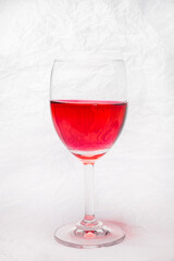 Glass of red  wine on a white crumpled paper background.