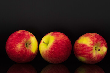 Three juicy organic apples, close-up, isolated on black.