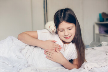 Cute european girl child with a white rat in her arms. Children and pets.