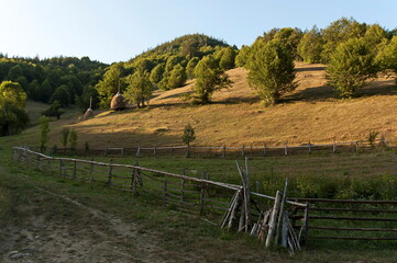 View of a mountain pasture with traditional hayrick for the winter, forest and a vegetable garden near the village of Vasilyovo, Bulgaria   